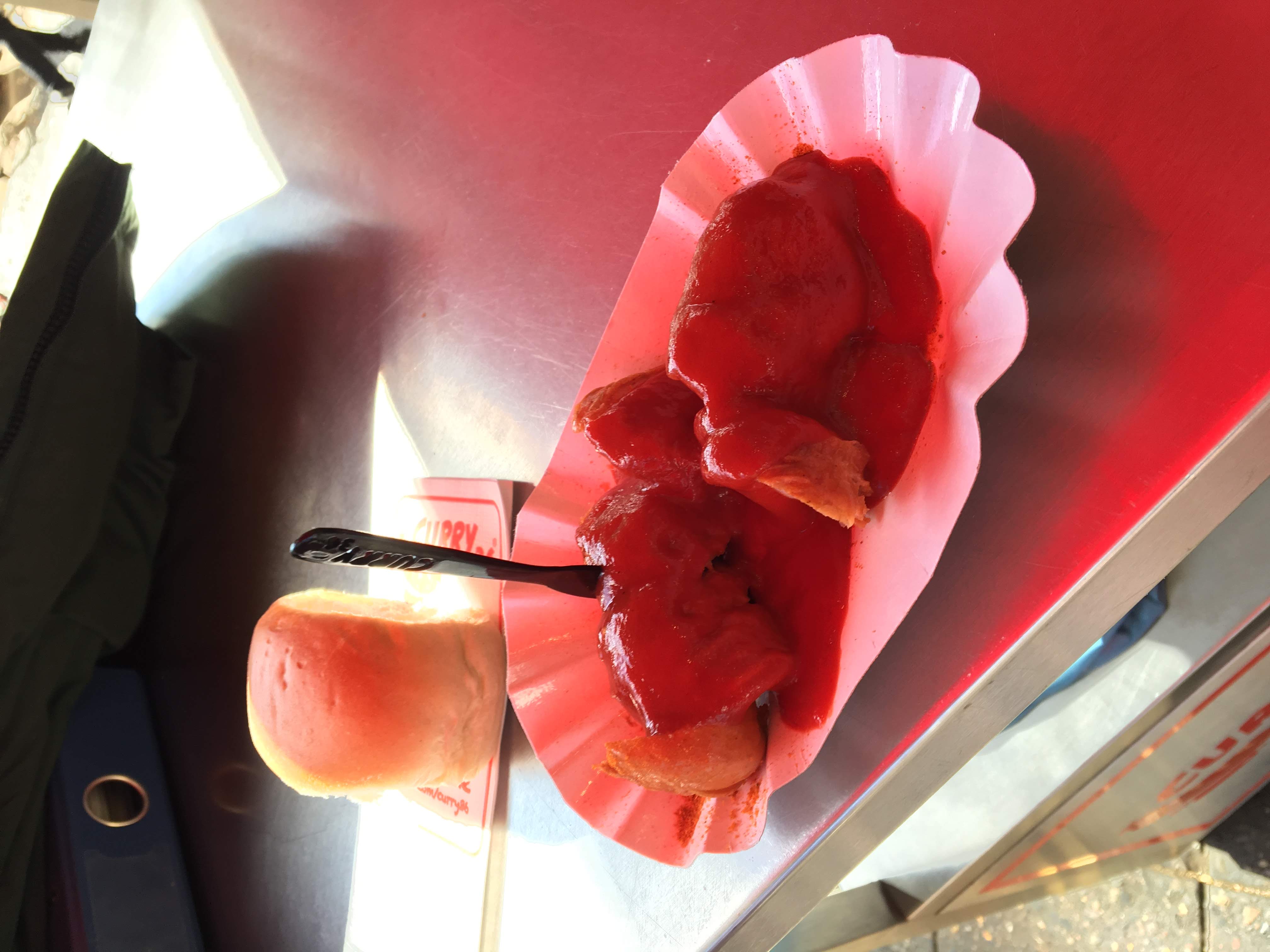 Currywurst on a paper plate with a plastic fork
