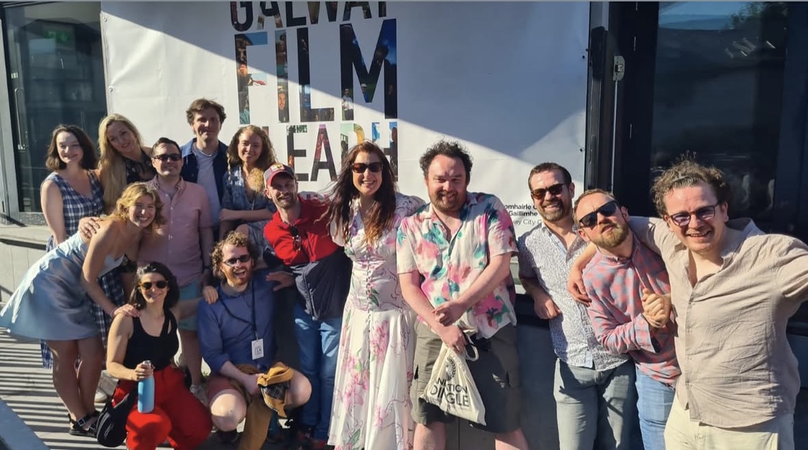 A group photo of the cast & crew of The Badger of Ballybog in front of a sign for the Galway Film Fleadh.