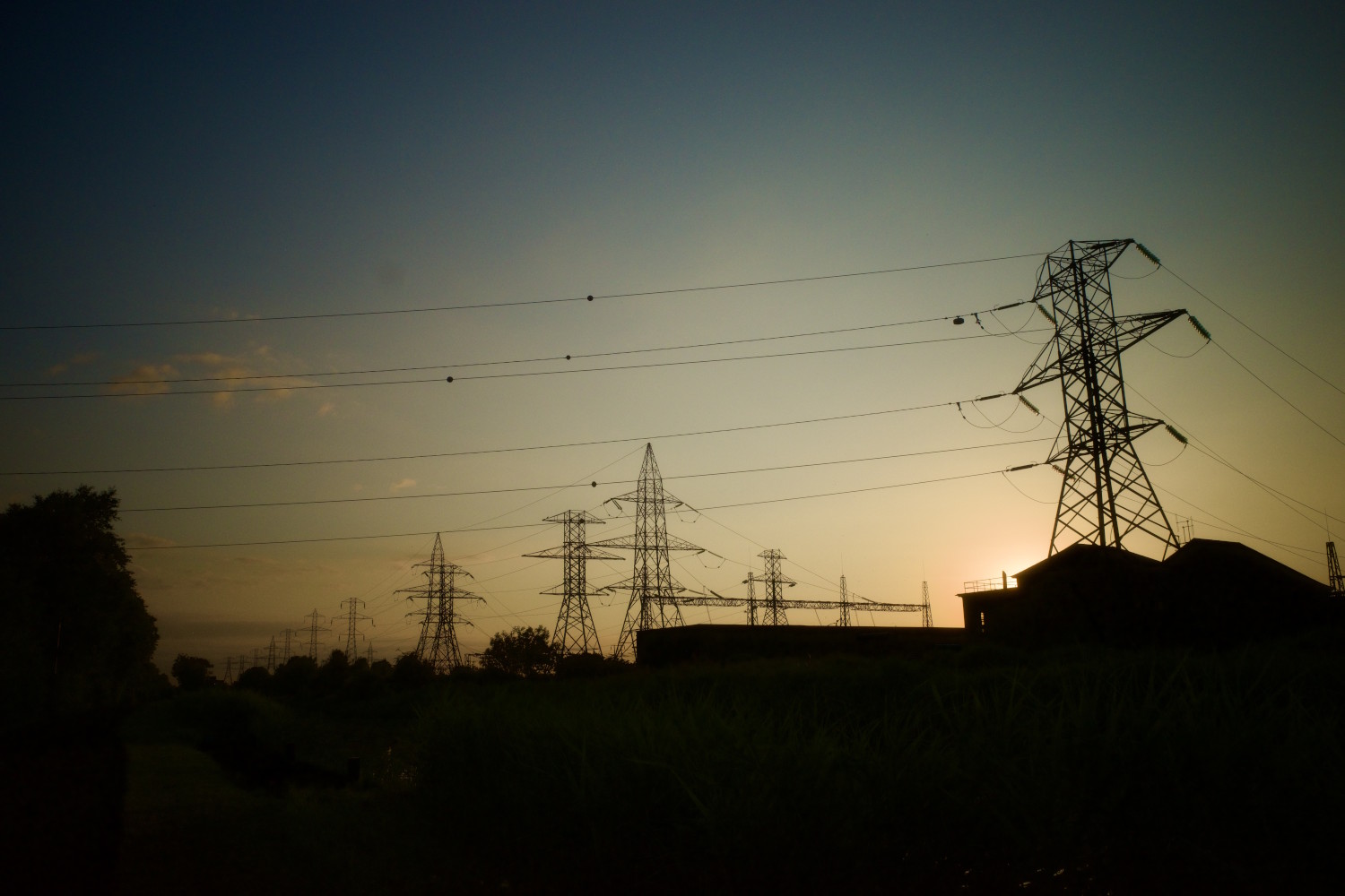 Power lines and pylons in silouette against a sunset.